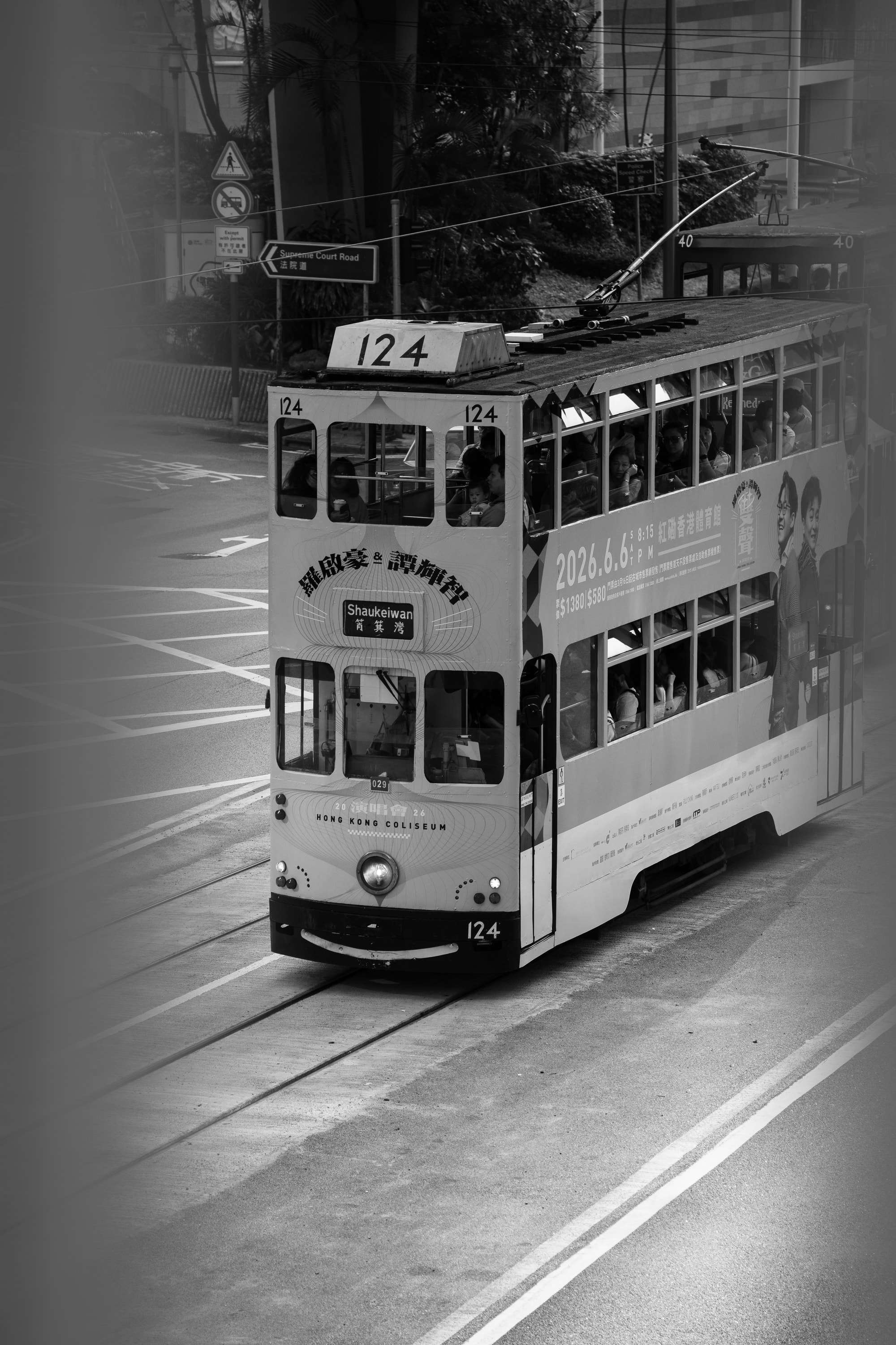Black and white: double-decker tram number 124, bound for Shau Kei Wan, runs along Queensway past trees and road signs.