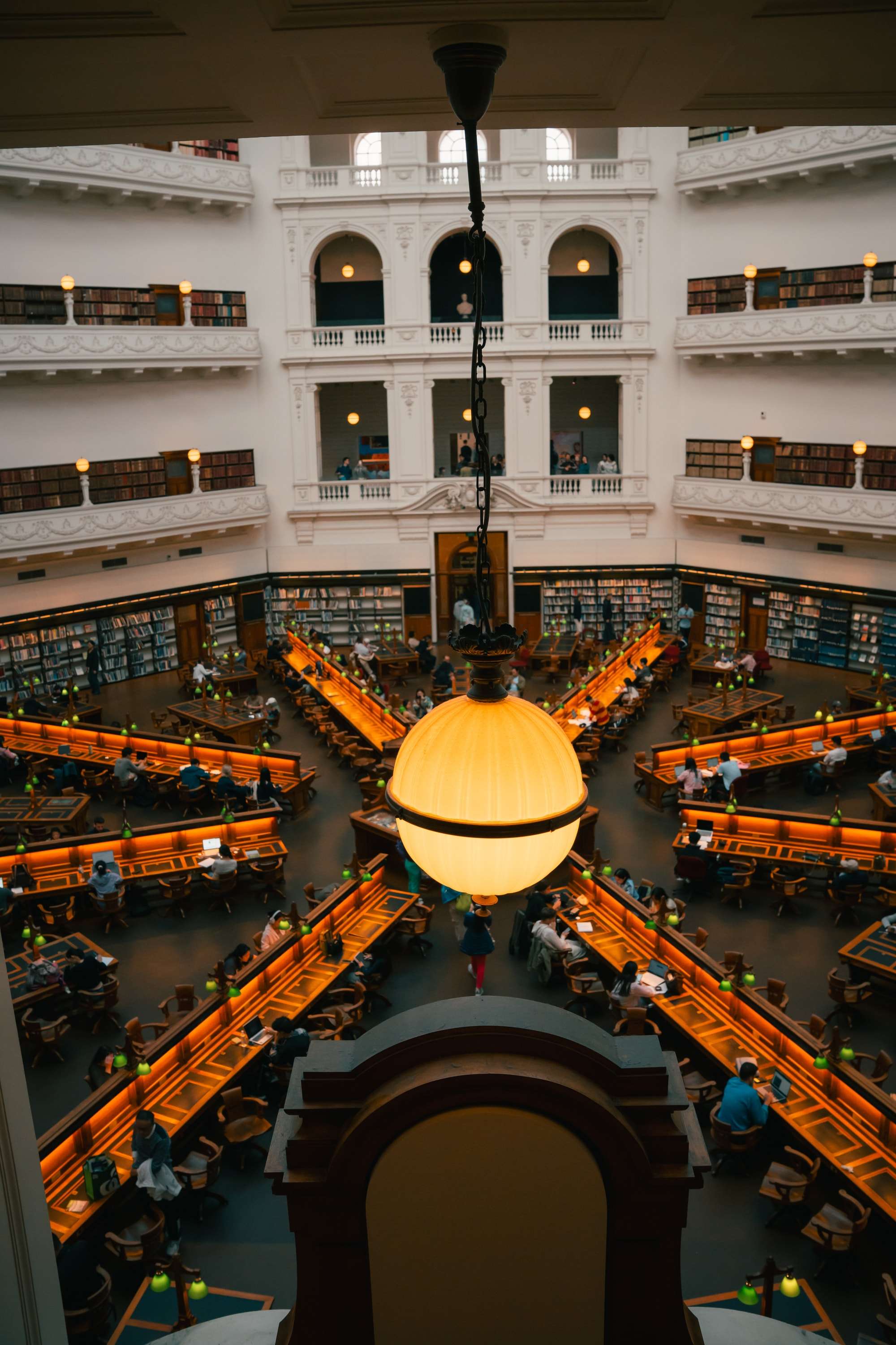 Looking down into the octagonal La Trobe Reading Room from an upper gallery, a globe lamp in the foreground and desks radiating out below.